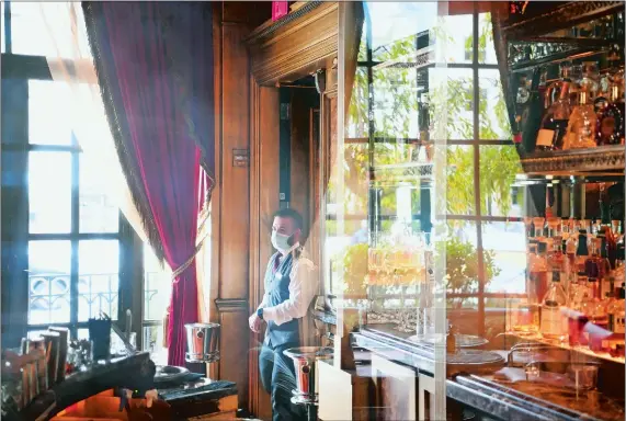  ?? MATT MCCLAIN/ THE WASHINGTON POST ?? Bartender Diego Trujillo is seen through plexiglass in the lounge of the St. Regis Hotel, one of Washington’s few luxury hotels that has not closed during the pandemic.