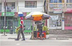  ??  ?? KINSHASA: A man stands by a street stall as another one walks past him yesterday.