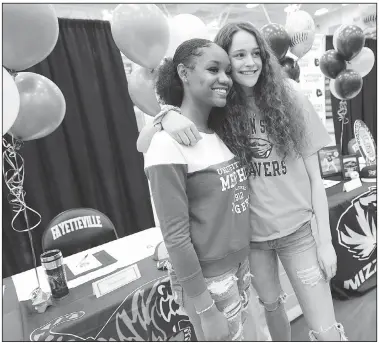  ?? NWA Democrat-Gazette/ANDY SHUPE ?? Coriah Beck (left) and Sasha Goforth embrace as family members take photos Wednesday before the start of a signing ceremony at Fayettevil­le High School. Beck signed to play for Memphis while Goforth signed to play for Oregon State.