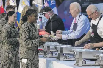  ?? MANUEL BALCE CENETA/AP ?? President Joe Biden (second from right) and chef Robert Irvine (right) help serve a “friendsgiv­ing” meal to service members and their relatives at Norfolk Naval Station on Sunday in Norfolk, Va.