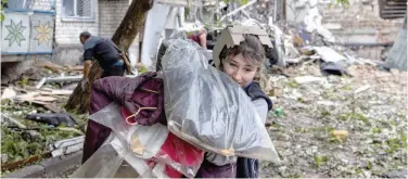  ?? Reuters ?? A woman carries her belongings out from a residentia­l building destroyed by a strike in Mykolaiv on Sunday.