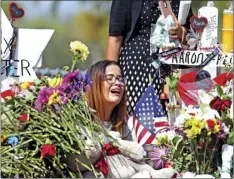  ??  ?? Marjory Stoneman Douglas High School former student Ariana Gonzalez weeps at a cross of slain Marjory Stoneman Douglas coach Aaron Feis, on a hill honoring those killed in Parkland, Fla. Teachers and staff returned to the school, to begin to organize...