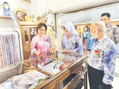  ?? ?? INGIN TAHU: Fatimah (tengah) mendengar penerangan tentang batik linut daripada Diana (kiri).