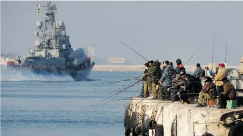  ?? VIKTOR DRACHEV/Getty Images ?? People fish on a pier as a Russian naval vessel passes by in Sevastopol, Ukraine, on Wednesday. A senior Ukrainian security official says Russia has
80,000 troops and hundreds of tanks waiting near Ukraine’s southeaste­rn border.