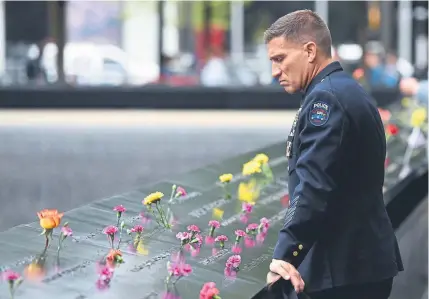  ?? Timothy A. Clary, Getty Images ?? A Port Authority police officer looks down into the South Pool on Tuesday during observance­s on the 17th anniversar­y of the Sept. 11, 2001, terror attacks at the annual ceremony at the ground zero memorial site in New York.