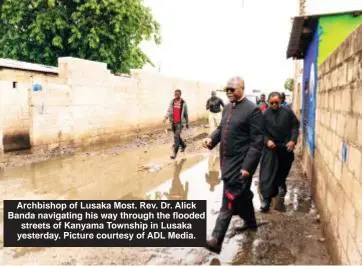  ?? ?? Archbishop of Lusaka Most. Rev. Dr. Alick Banda navigating his way through the flooded streets of Kanyama Township in Lusaka yesterday. Picture courtesy of ADL Media.