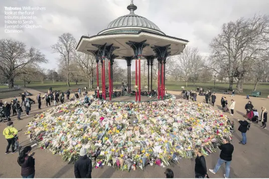  ??  ?? Tributes Well-wishers look at the floral tributes placed in tribute to Sarah Everard on Clapham Common