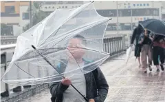  ?? AP ?? A boy tries in vain to use an umbrella in Fujisawa, Japan, yesterday.