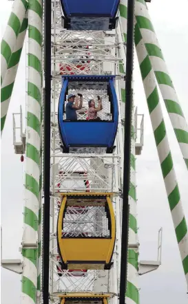  ?? [PHOTOS BY STEVE SISNEY, THE OKLAHOMAN] ?? Fairgoers ride the giant Ferris Wheel at the Oklahoma State Fair on Thursday.