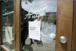  ?? MATT SLOCUM — THE ASSOCIATED PRESS ?? A man tapes a sign to a door at a Starbucks Coffee shop, Tuesday in Philadelph­ia. After the arrests of two black men, Rashon Nelson and Donte Robinson, at this location, Starbucks will close more than 8,000 stores nationwide on Tuesday to conduct...