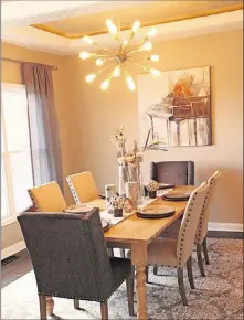  ??  ?? LEFT: The tray ceiling in the formal dining room is centered with an unusual designer chandelier suggesting a starburst in modern form.