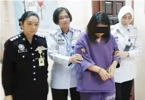  ??  ?? JOAN (kiri) turut mengiringi suspek yang memakai baju lokap berwarna ungu dan tangan bergari selepas perintah reman dikeluarka­n.