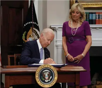  ?? /EFE ?? Acompañado de su esposa Jill Biden, el presidente firmó el acuerdo votado por el Congreso que restringe mínimament­e el acceso a las armas.