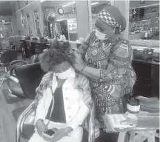  ?? JENNY JARVIE Los Angeles Times ?? Mariam Cisse, 46, the owner of Laze Hair Braiding in Atlanta’s historic black West End, braids client Britany Granger’s hair after Gov. Brian Kemp’s ruling allowing companies to reopen. ‘I don’t have any choice. I have no money.’