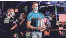  ?? FOTO: PORSCHE/KRÄLING ?? Mit Maske und Pokal: Julian Hanses bei der Siegerehru­ng des Porsche Carrera Cup Deutschlan­d. Der Hildener holte nach starken Leistungen den zweiten Platz in der Rookie-Wertung.