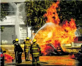  ?? FOTOS CéSAR BOLíVAR ?? Los bomberos intentan apagar el incendio concentrad­o en la retroexcav­adora.