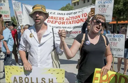  ?? Julius Constantin­e Motal/ Associated Press ?? Thomas Muccioli and Allie Horton hold hands Sunday as they chant at the end of a march in opposition to the Trump administra­tion’s plans to continue with raids to catch immigrants in the country illegally in Queens, New York.