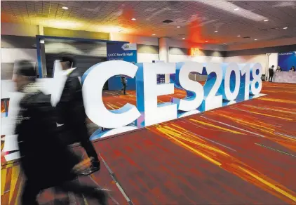  ?? Richard Brian ?? Las Vegas Review-journal @vegasphoto­graph People walk past a #CES2018 sign Monday at the Las Vegas Convention Center during setup for the technology expo.