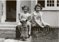  ??  ?? Princess Elizabeth and Princess Margaret play with a corgi outside the Welsh House at the Royal Lodge, Windsor, June 1936