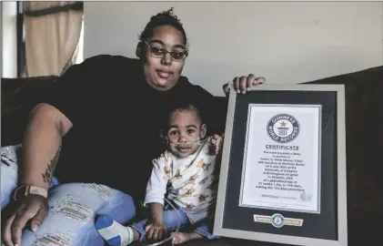  ?? AP PHOTO/BUTCH DILL ?? Curtis Means and his mother, Michelle Butler, sit with their certificat­e from the Guinness Book of World Records at their home in Eutaw, Ala., on March 23.