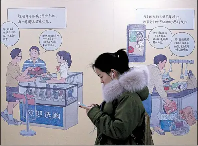  ?? AP/ANDY WONG ?? A woman walks past a mural depicting iPhone buyers Thursday at a subway station in Beijing. Apple’s $1,000 iPhone is a tough sell to Chinese consumers.