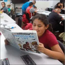  ??  ?? Inuyasha Alcantar, 10, reads “Prehistori­c Life” after school on Friday as part of the YES program at Belleview Elementary.