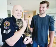  ?? DARREN STONE, TIMES COLONIST ?? Victoria police Sgt. Byron Edwards cradles Daisy the tabby cat, back with her owner, Grant Harbar.
