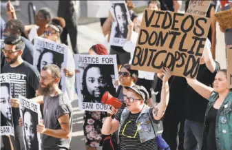  ?? John Minchillo / Associated Press ?? Protesters chant as they march on the University of Cincinnati campus demanding that a white former police officer be tried a third time in the fatal shooting of an unarmed black motorist.