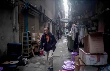  ?? – AFP photo ?? A man smokes a cigarette as he walks down an alleyway in Hong Kong. Property prices have more than doubled in the last decade, and many city centre private flats sell for at least US$25,000 per square foot.