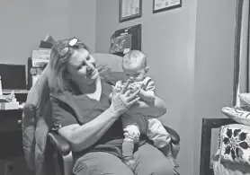  ?? LUCY GRINDON/NORTH COUNTRY PUBLIC RADIO ?? ABOVE: North Country midwife Sunday Smith holds a child she delivered. The child was back at Smith's birth center in Potsdam for a prenatal visit for her mother.