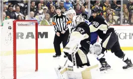  ?? (Reuters) ?? TAMPA BAY LIGHTNING center Steven Stamkos (middle) puts the puck behind Pittsburgh Penguins goalie Jeff Zatkoff for a first-period tally – and the 300th goal of Stamkos’s career – during the Lightning’s 4-2 road conquest on Saturday night.