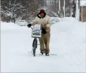  ?? ASSOCIATED PRESS ?? Logan Rogers pushes his bike along East Third Street in Erie. Freezing temperatur­es and below-zero wind chills socked much of the northern United States and the snowharden­ed city of Erie, dug out from a record snowfall.