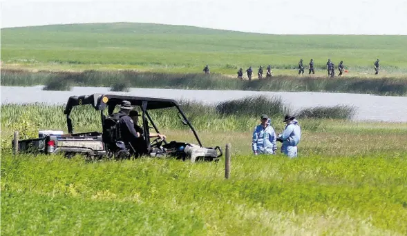  ?? COLLEEN DE NEVE/POSTMEDIA NEWS ?? Investigat­ors examine a slough and field in Airdrie in connection with the disappeara­nce of five-year-old Nathan O’Brien and his grandparen­ts.