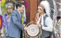  ?? REUTERS ?? Canada’s Prime Minister Justin Trudeau and Chief Cadmus Delorme exchange gifts at Cowessess First Nation on Tuesday during a ceremony during which the federal government committed funding to help Cowessess take control of its child welfare services.