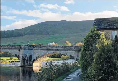  ?? DAVE HAGE/MINNEAPOLI­S STAR TRIBUNE PHOTOS ?? A high Yorkshire fell rises behind the River Wharfe and the five-arch bridge, a well-known landmark in Burnsall.