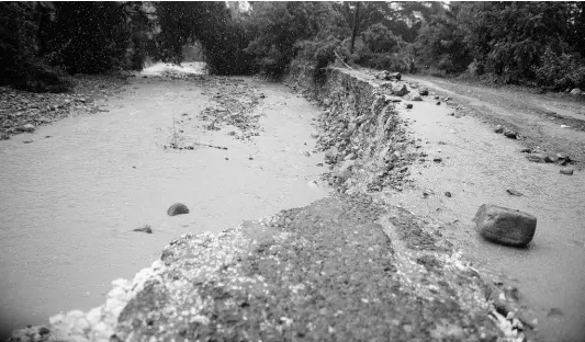  ?? GLADSTONE TAYLOR/MULTIMEDIA PHOTO EDITOR ?? Silt covers the Georgia main road in St Thomas as a section A section of the roadway is being eroded by a river on Friday October 2. The NWA boss has noted the physical damage caused to road by landslides but says most of the roads being eroded across the island are because of poor drainage and inadequate infrastruc­ture.