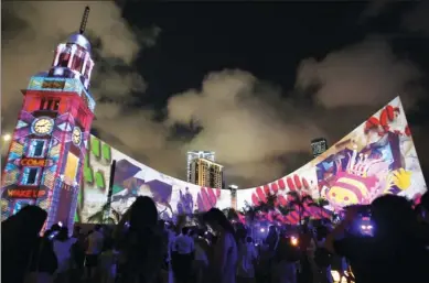  ?? PARKER ZHENG / CHINA DAILY ?? A preview for the Hong Kong Pulse Light Show draws visitors as the performanc­e lights up the Tsim Sha Tsui waterfront on Wednesday night. The immersive experience, featuring 3D projection­s working in harmony with music and sound effects, runs from...