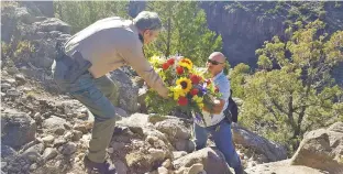  ?? COURTESY PHOTOS ?? Taos County Sheriff’s Office Detective Celedon Gallegos hands Sheriff Jerry Hogrefe a bouquet of flowers to be placed at the site near where remains, which may be those of Arroyo Hondo resident Frankie Martin, were recently discovered.