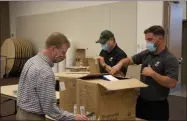  ?? SARATOGA COUNTY CHAMBER OF COMMERCE PHOTO ?? Saratoga County Chamber of Commerce President Todd Shimkus, left, assists in unpacking a large mask donation from UniFirst.