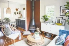  ??  ?? Ashley Redmond cultivates an airy feel in her home despite its tiny footprint: Rattan furniture, from top, and white walls keep things light; the designer at her desk; the vintage wood-burning stove separates kitchen from living area; wall-mounted...