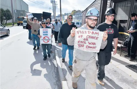  ?? JOSH REYNOLDS/AP ?? Justin Paetow, front, holds a sign while a group protests against a COVID-19 vaccine mandate Friday at Bath Iron Works in Bath, Maine.