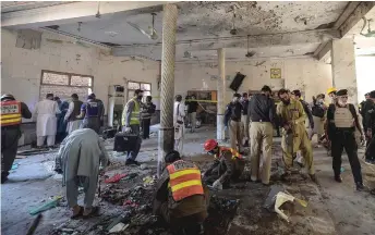  ?? — AFP photo ?? Security officials examine the site of a blast at a religious school in Peshawar.