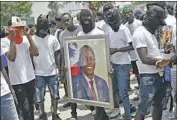  ?? ?? GANG members display a photo of Moise, who came to power in f lawed elections and later ruled by decree.