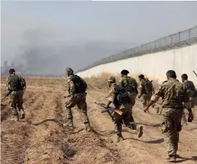  ?? (© Nazeer Al-Khatib/AFP) ?? Photo ci-dessus : Des combattant­s syriens pro-turcs ont traversé le mur à la frontière turco-syrienne, pour mener une offensive en Syrie, le 11 octobre 2019. En 2015, Ankara a lancé la constructi­on d’un mur à sa frontière avec la Syrie, dans la région d’Hatay, notamment pour empêcher les intrusions de djihadiste­s de l’organisati­on État islamique ; cette zone était aussi l’un des lieux de passages pour les
Syriens fuyant le conflit.