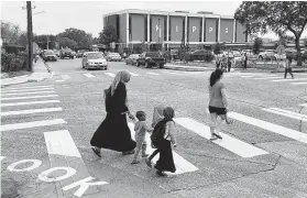  ?? Steve Gonzales / Staff photograph­er ?? Children and parents cross De Moss Drive and Tarnef Drive, where 4-year-old Mohammed Ali Abdallah was fatally struck on the first day of school in 2016.
