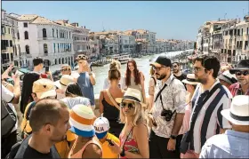  ?? (The New York Times/Francesca Volpi) ?? Tourists gather on the Rialto Bridge in Venice, Italy. After three years of pandemic restrictio­ns, travelers are flocking to Europe in record numbers despite high airfares, limited accommodat­ions and crowded sites.
