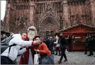  ?? AP/CHRISTOPHE ENA ?? Tourists in Strasbourg, France, get a photo with Santa at the Christmas market, which reopened Friday with a heavy police presence after it was closed for two days.