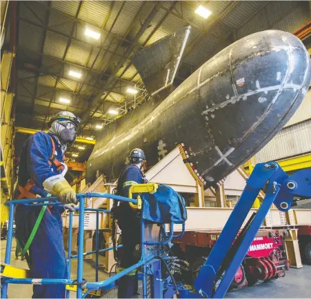  ?? ARLEN REDEKOP ?? Workers at Ideal Welders prepare the 100-tonne “bulbous nose” bow for a navy ship to be wheeled out the door of the Annacis Island shop on Tuesday. The ship's bow will be barged to the North Shore starting today. It passes under the Lions Gate Bridge around 6 a.m. Thursday.