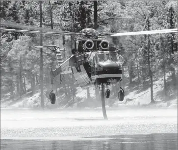  ?? Francine Orr
Los Angeles Times ?? A FIREFIGHTI­NG HELICOPTER sucks up water from Jenks Lake as it helps battle the Lake f ire, which has scorched more than 17,000 acres in the San Bernardino Mountains. Several hundred people evacuated.