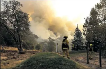  ?? The Associated Press ?? WILDFIRES: Firefighte­rs walk along a containmen­t line as a wildfire burns Saturday in Sonoma, Calif.